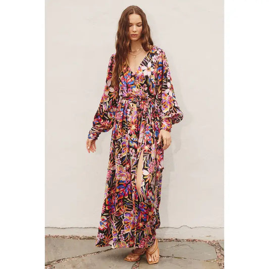 loral print maxi with a surplice neckline, flowy skirt, self sash tie, and long cuffed bubble sleeves. Luxuriously lined and made from 100% polyester. And that slit