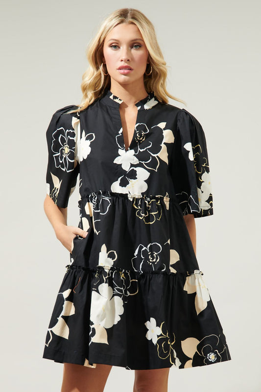Oh so chic. Perfect for both casual and semi formal outings, this dress will be your new wardrobe fave. Classic outlined florals mixed with silhouette style motifs decorate a playful mini dress with a split neckline that's framed by gathered short sleeves. It maintains an A line frame with ruffle lined tiers.