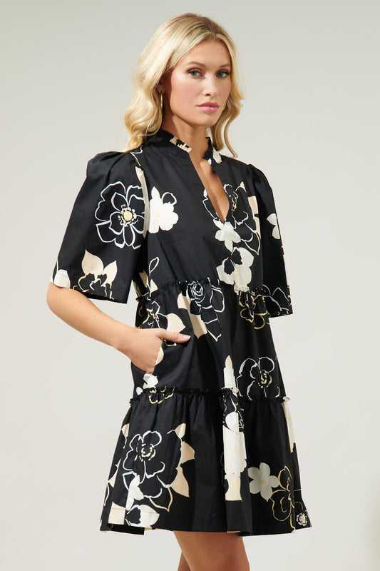 Oh so chic. Perfect for both casual and semi formal outings, this dress will be your new wardrobe fave. Classic outlined florals mixed with silhouette style motifs decorate a playful mini dress with a split neckline that's framed by gathered short sleeves. It maintains an A line frame with ruffle lined tiers.