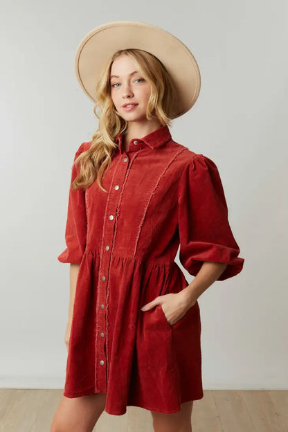 Corduroy babydoll mini dress, collared, half puff sleeves, button-down closure and pockets.
