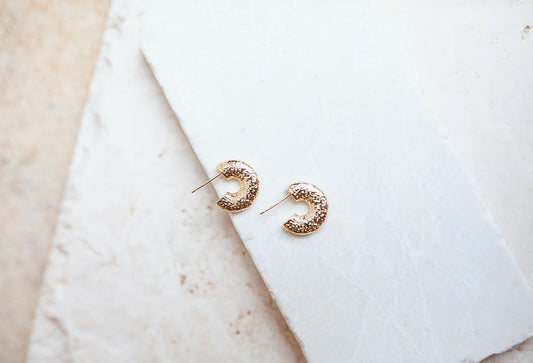 These Hammered Huggie Hoop earrings are the perfect for any occasion. Exquisitely crafted with 24kt gold plating and non-tarnishing these earrings are designed to to be worn every day. Hypoallergenic and water-resistant, they measure 17mm.