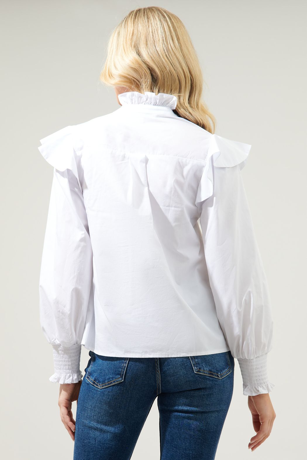 Add this classic poplin blouse to your wardrobe. An easy-to-style top that features a ruffle mock neckline with a button front. Ruffle cap shoulder details top a balloon sleeve with a smocked cuff. Wear this crisp, cool top tucked into high rise denim for an effortless look.
